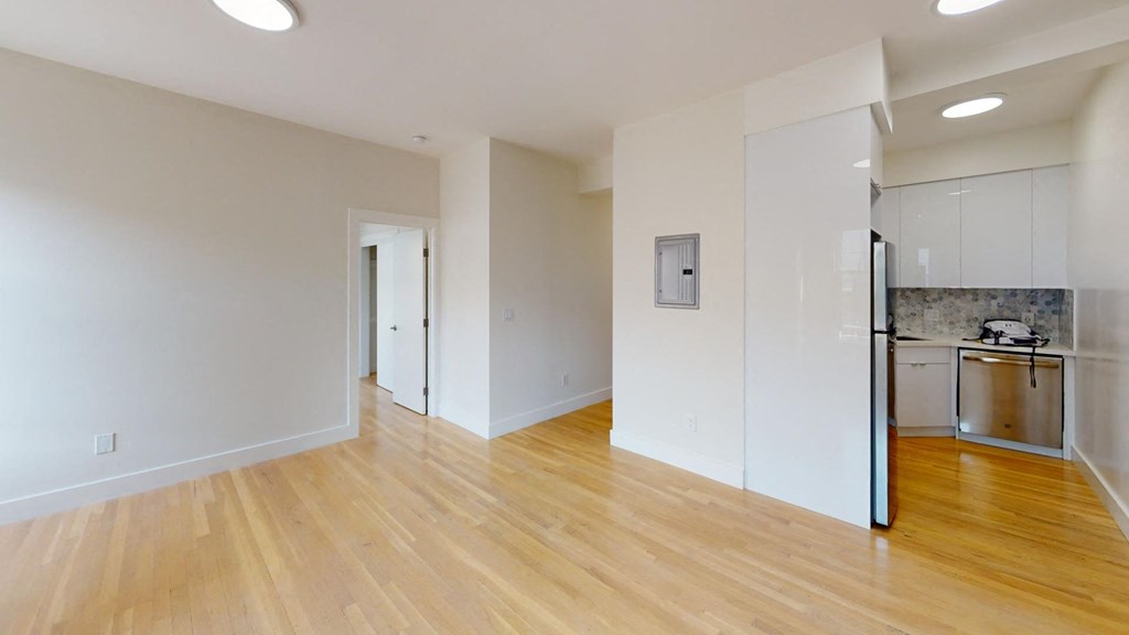 a renovated living room and kitchen with wood floors and white walls
