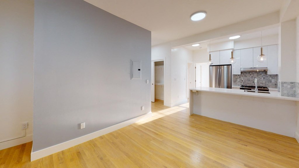 a renovated living room and kitchen with white walls and wood floors