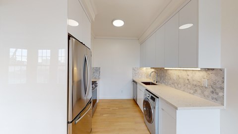 A modern kitchen with a refrigerator, washing machine, and a countertop.