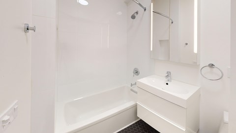A white bathroom with a tub, sink, and mirror.