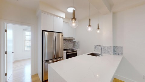 A kitchen with a white counter top and a stainless steel refrigerator.