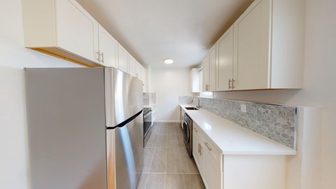 A kitchen with white cabinets and a stainless steel refrigerator.