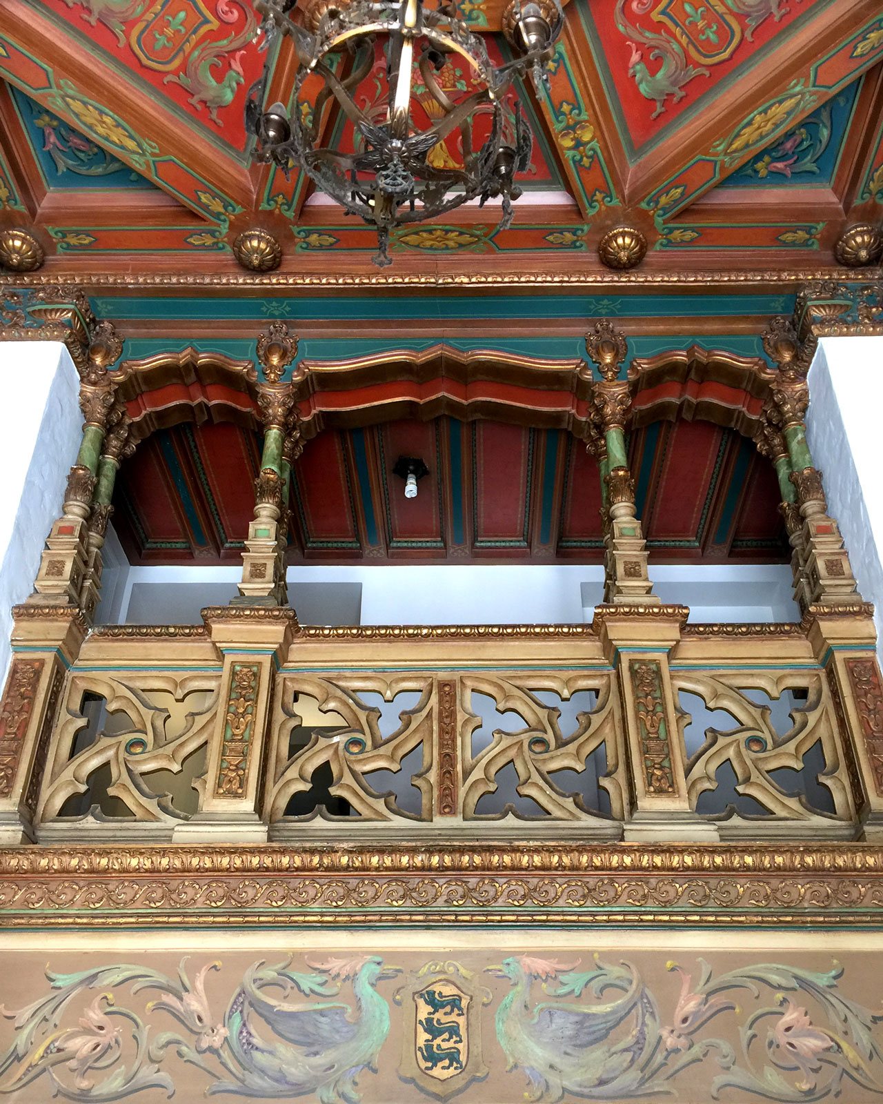 A chandelier hangs from an ornate ceiling.