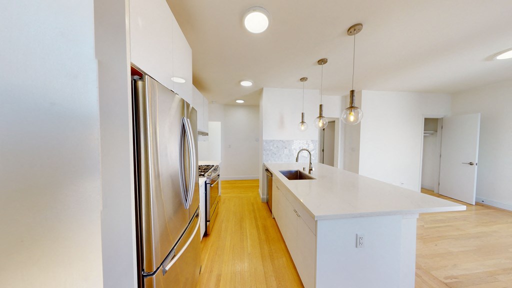 a kitchen with a white counter top and a stainless steel refrigerator
