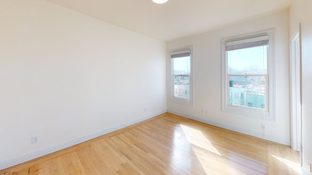 an empty living room with wood floors and two windows