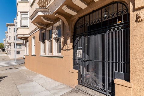 A black gate is in front of a tan building.