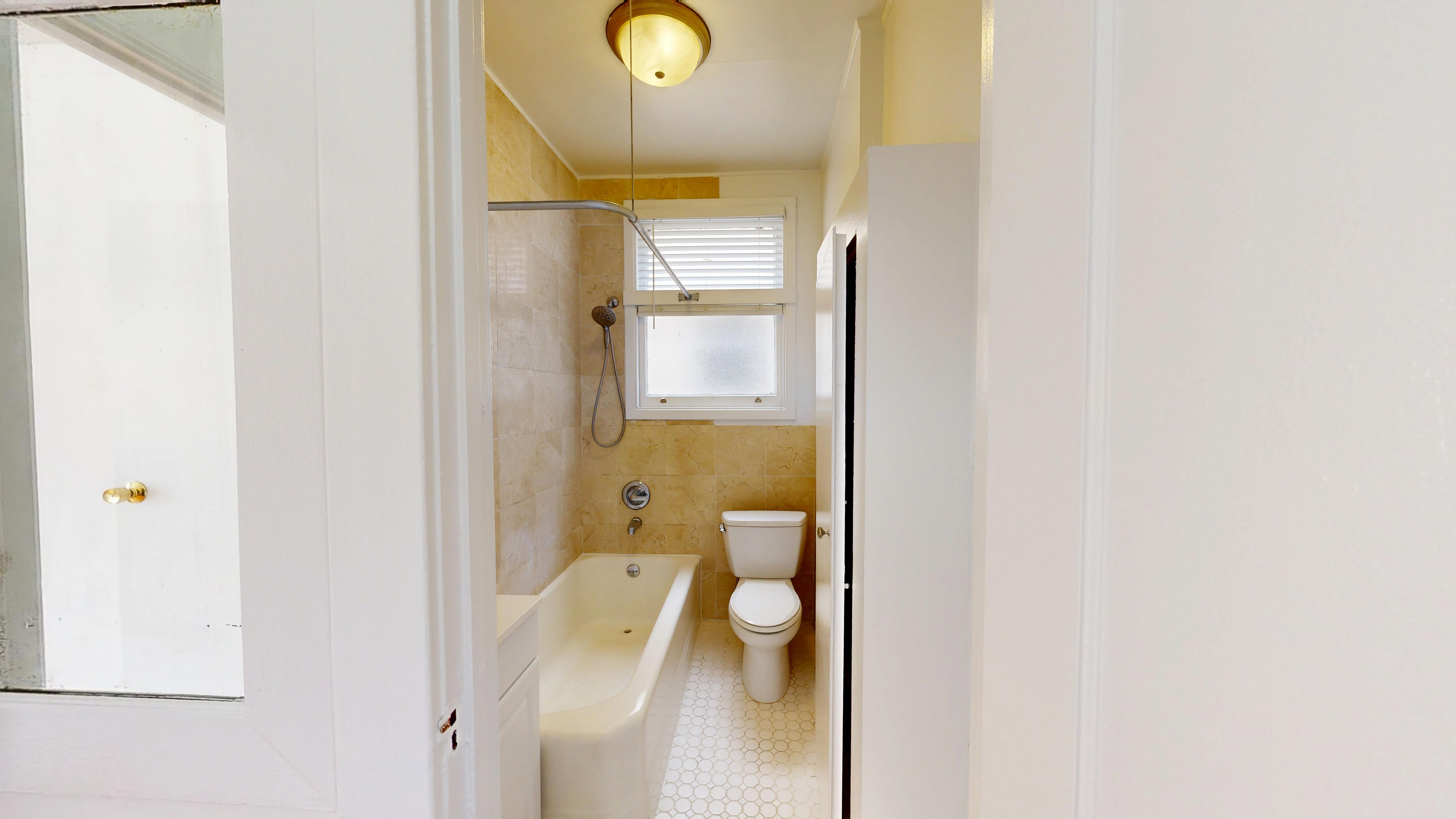 A white bathroom with a tub, toilet and sink.