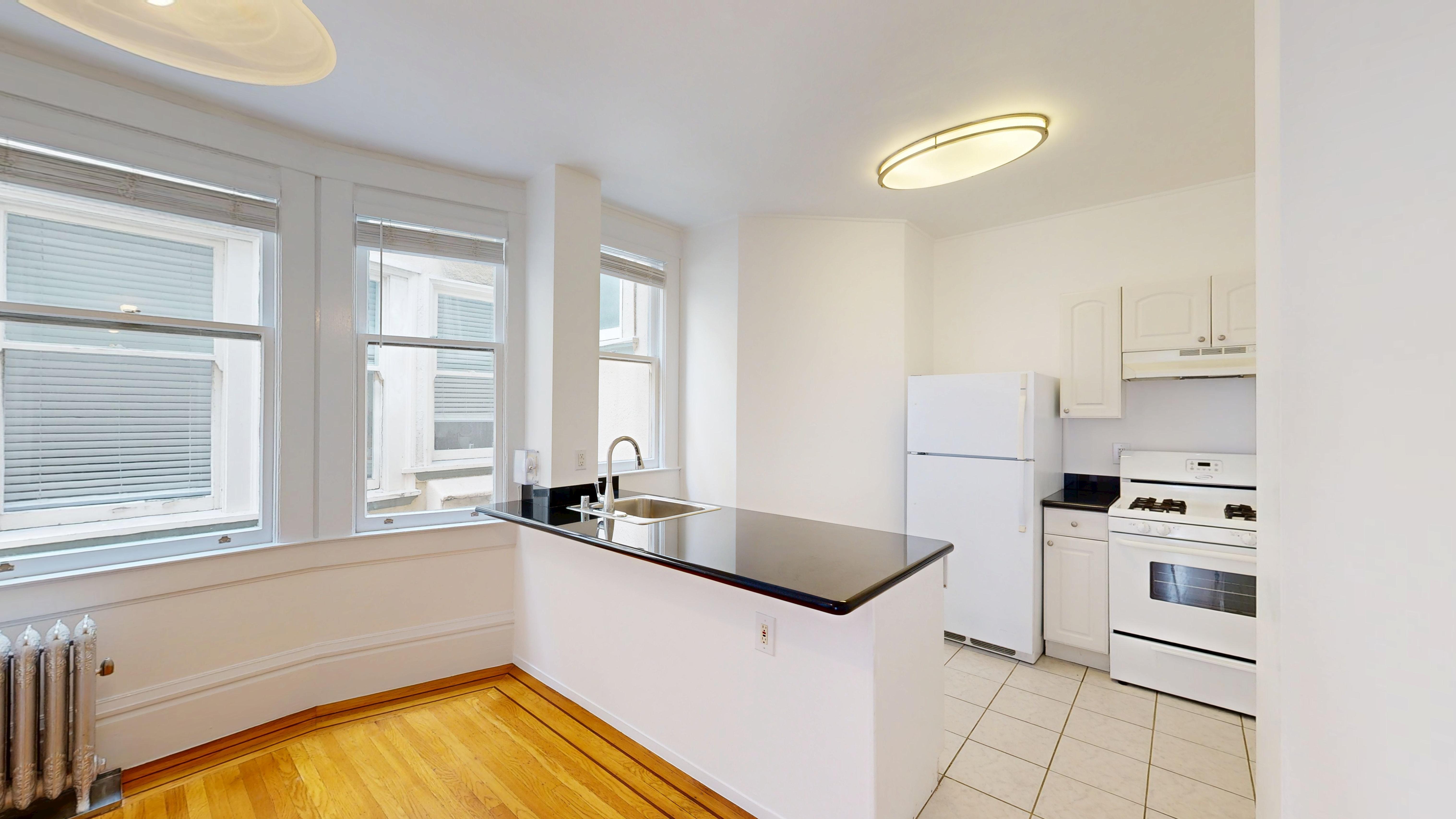 A kitchen with white appliances and wooden floors.