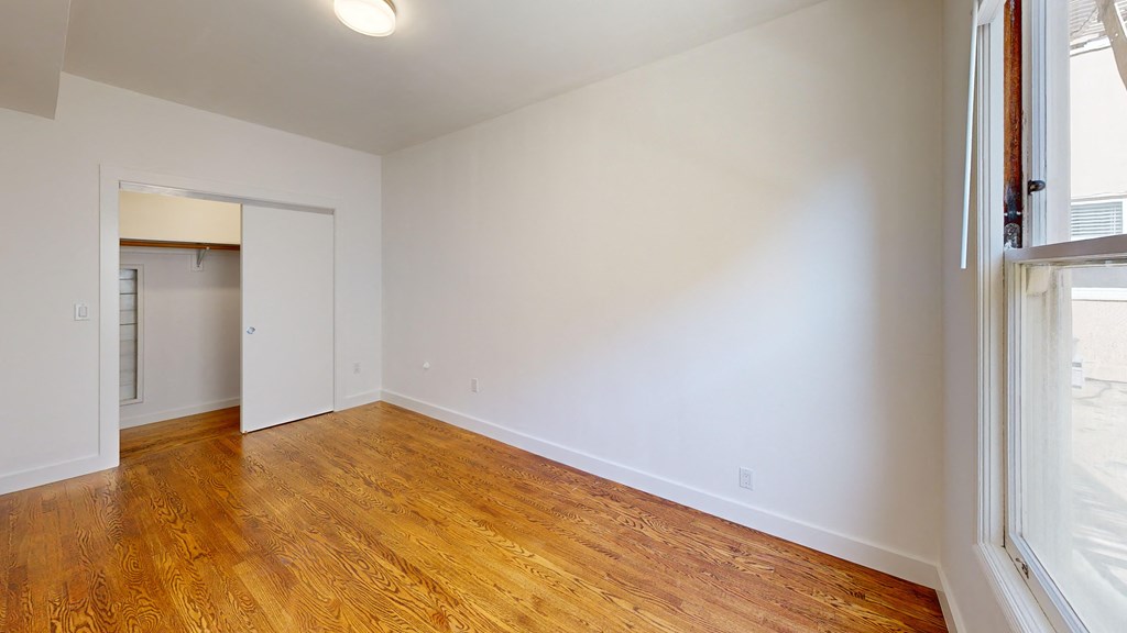 an empty living room with wood floors and white walls