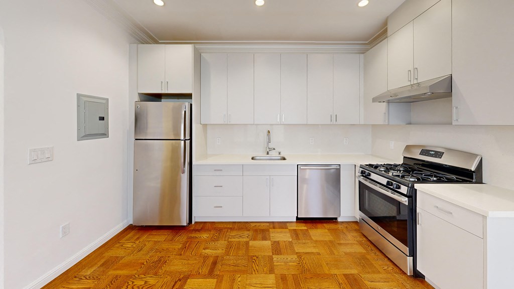 a white kitchen with stainless steel appliances and white cabinets