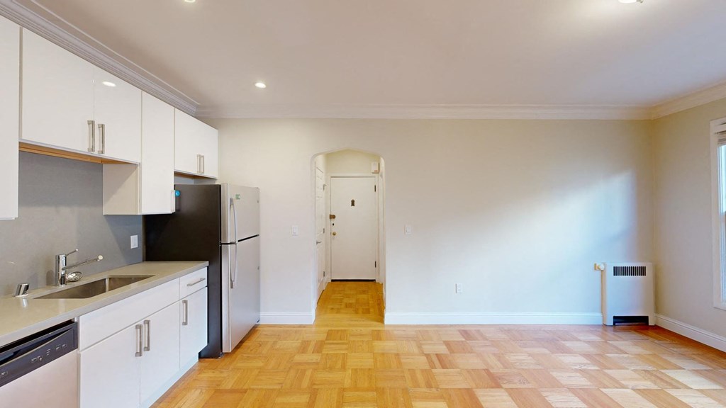 a renovated kitchen with white cabinets and a black refrigerator