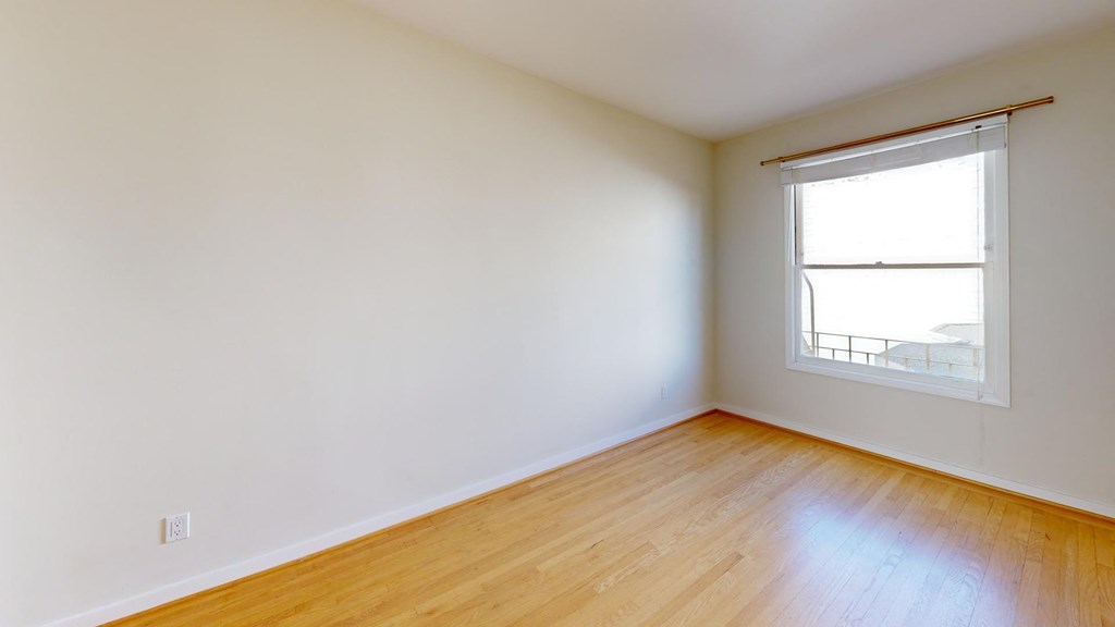 an empty room with a window and wooden floors