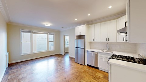 A kitchen with white cabinets and a wooden floor.