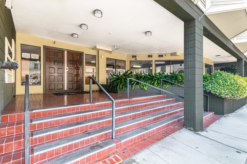 A set of stairs with red steps and a metal railing lead up to a building entrance.