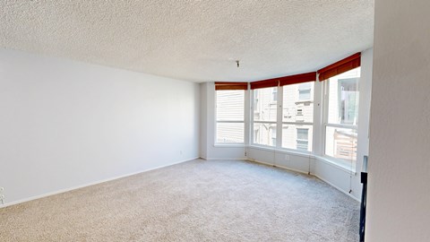 A room with a carpeted floor and a window with red curtains.