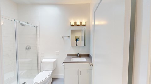 A white bathroom with a toilet, sink, and shower.