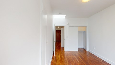 A long hallway with a wooden floor and white walls.