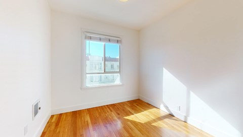 A room with a window and wooden flooring.