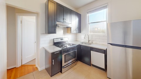 A kitchen with black cabinets and a stainless steel refrigerator.