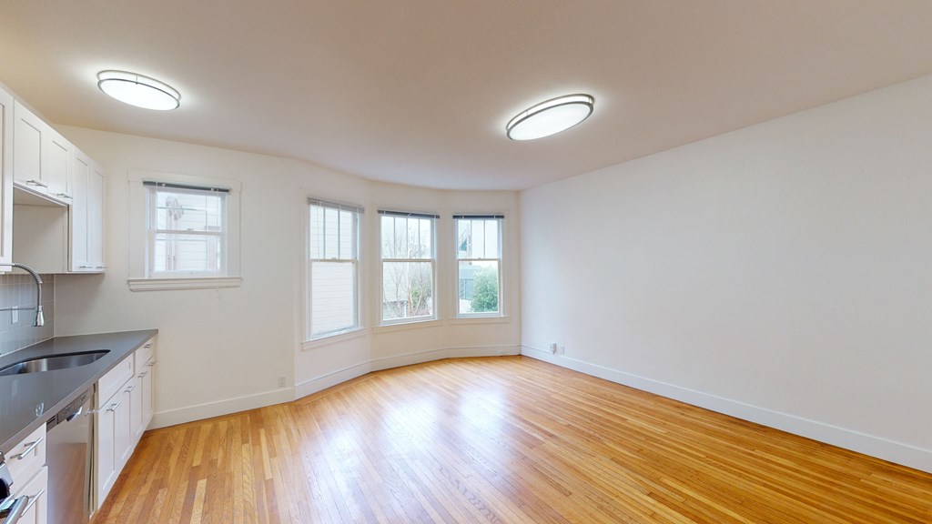 an empty kitchen and living room with wood floors and white walls