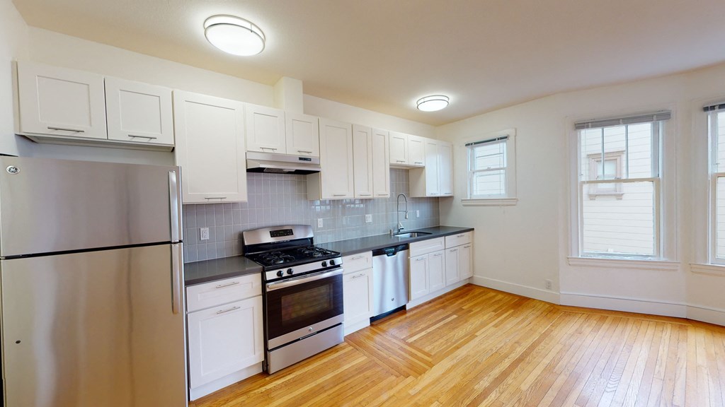 an empty kitchen with white cabinets and stainless steel appliances