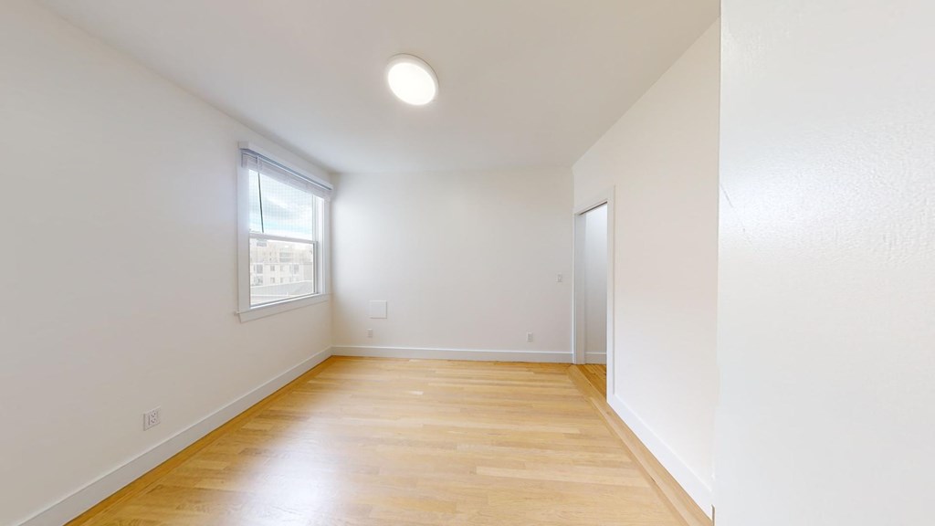 a living room with white walls and a window and wooden floors