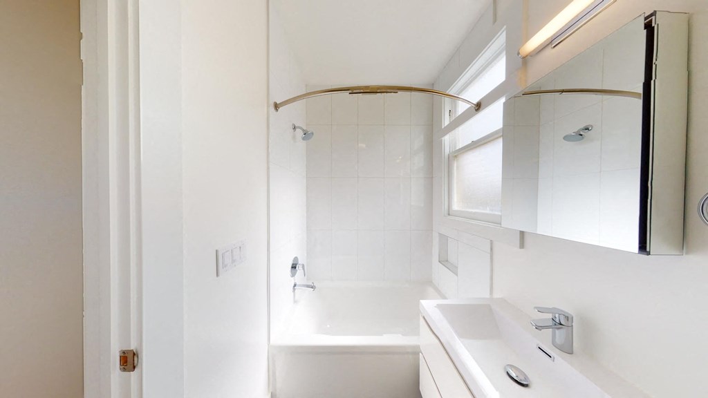 a white bathroom with a sink and a tub