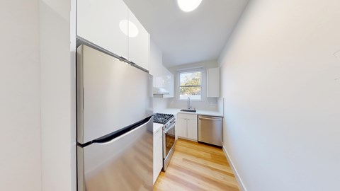 A kitchen with a refrigerator, sink, and stove.