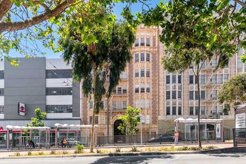A tall building with many windows is surrounded by trees.