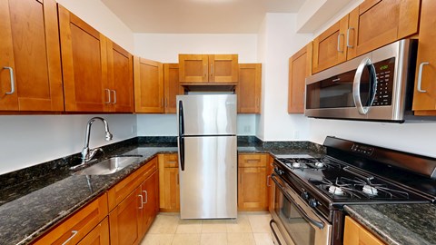 A kitchen with wooden cabinets and a stainless steel refrigerator.