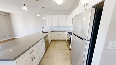 A kitchen with white cabinets and a black refrigerator.