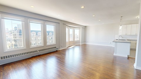 A spacious room with wooden floors and large windows.