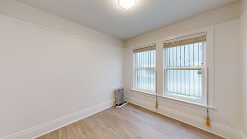 A room with a window and a radiator on the floor.