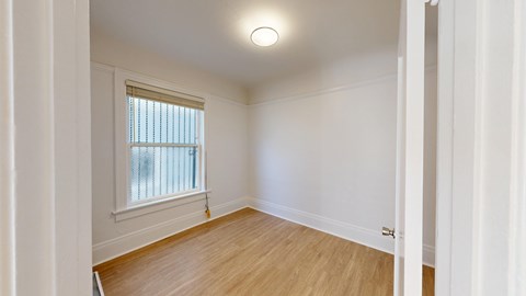 A room with a window and wooden flooring.