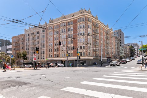 A street view of a city with a large building in the background and cars on the road.