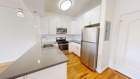 A kitchen with a stainless steel refrigerator and wooden floors.