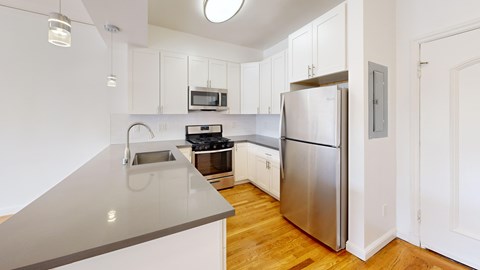 A kitchen with a stainless steel refrigerator and a grey counter top.