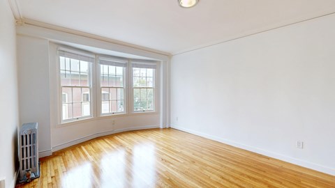 A room with a window and a radiator on the floor.