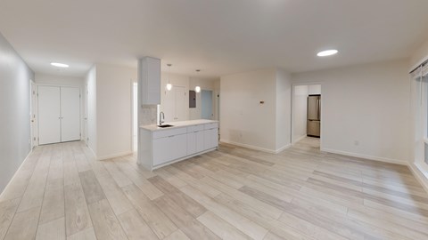 A spacious room with light wood flooring and white walls.