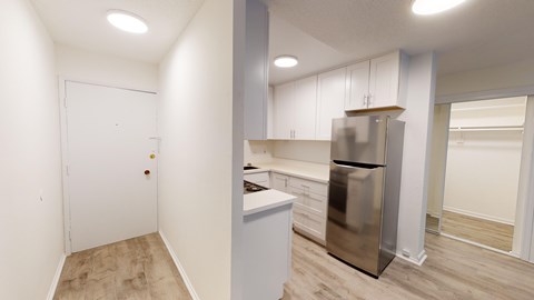 A kitchen with a stainless steel refrigerator and white cabinets.