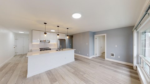 an open kitchen and living room with a white counter top and a large window