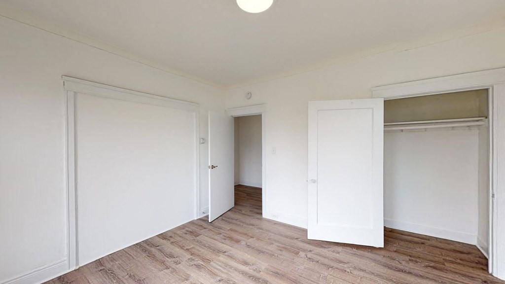 a bedroom with two closets and a wood floor