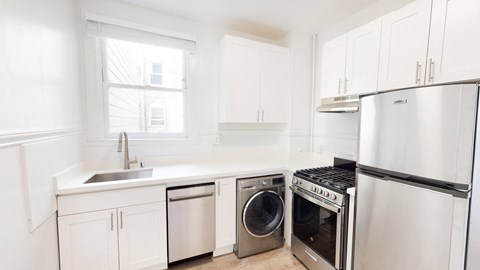 a white kitchen with stainless steel appliances and white cabinets