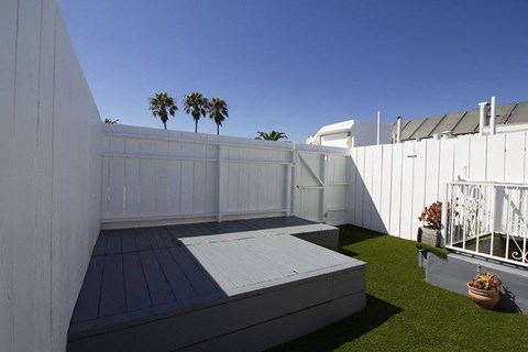 a small backyard with a wooden deck and a white fence