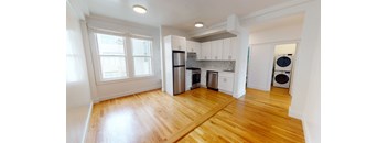a renovated kitchen with white cabinets and a wood floor