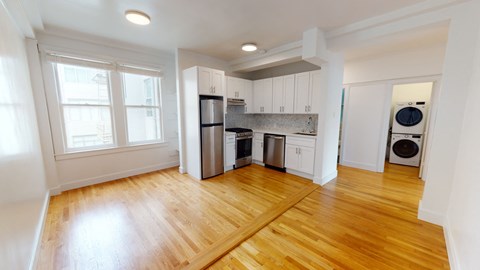 a renovated kitchen with white cabinets and a wood floor