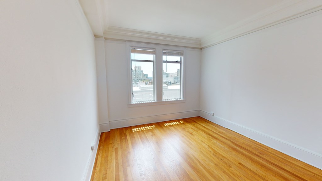 an empty room with wooden floors and two windows