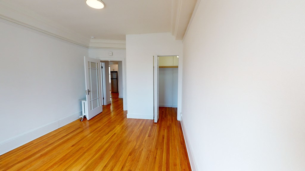 a living room and hallway with white walls and wood floors