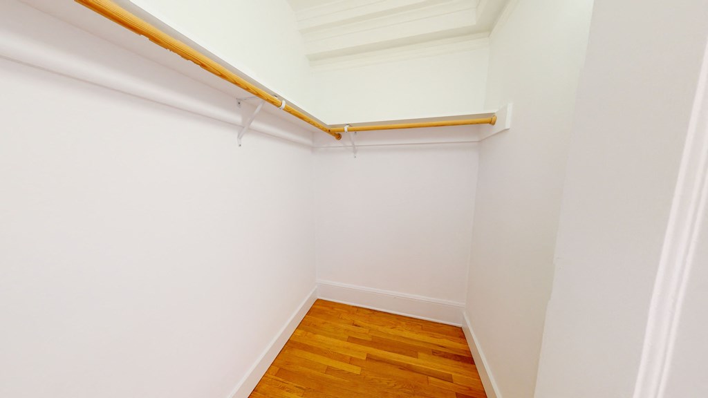 a room with white walls and wood flooring and a white closet