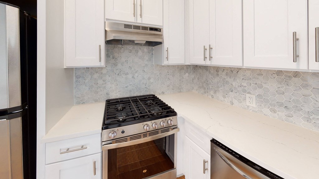 a white kitchen with a stove and white cabinets